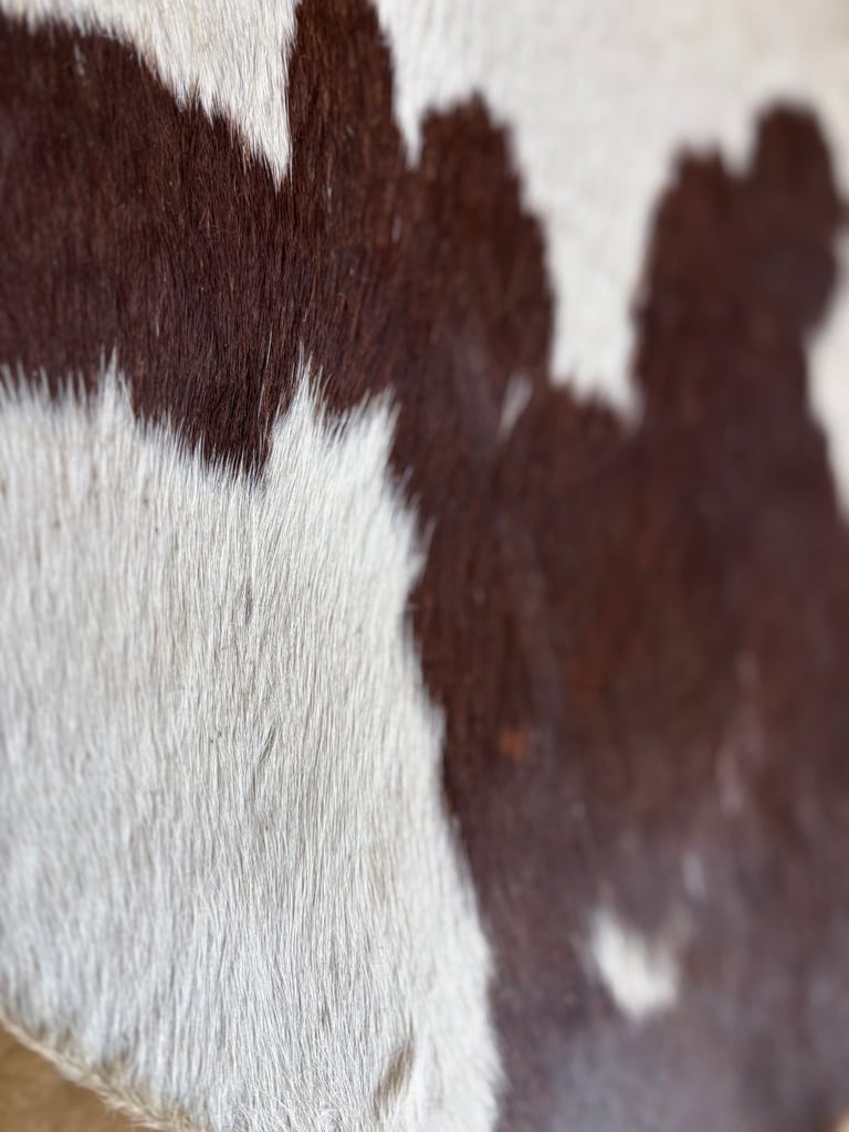 A Vintage Handmade 3 legged stool with cow hide seat.