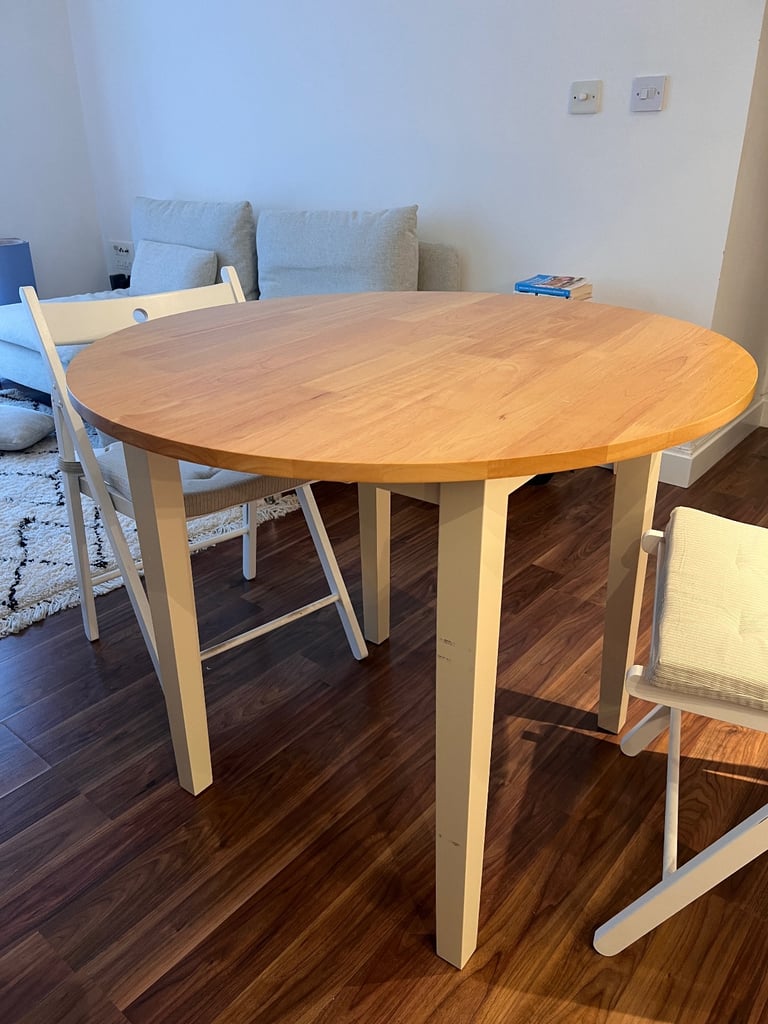 Round Wooden Dining Table with Two White Folding Chairs