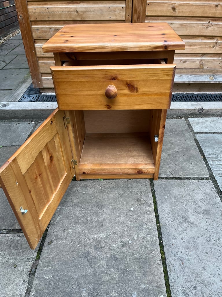 A knotted pine bedside cabinet with drawer and cupboard.