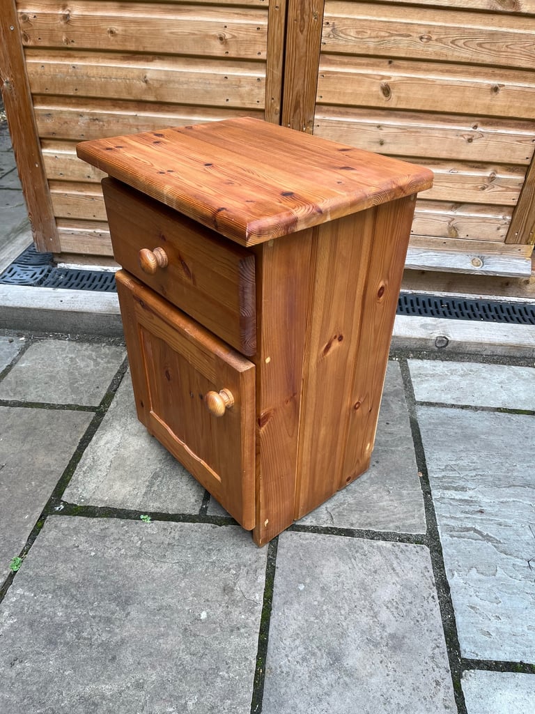 A knotted pine bedside cabinet with drawer and cupboard.
