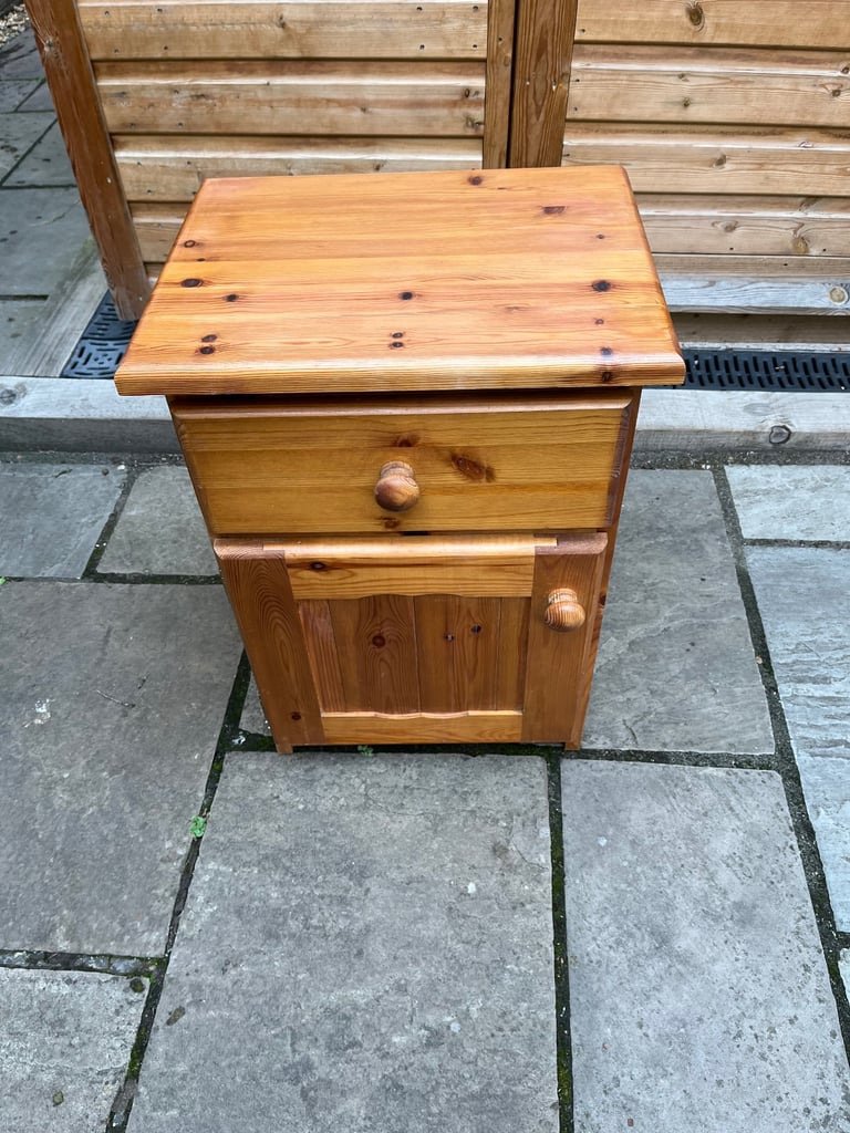 A knotted pine bedside cabinet with drawer and cupboard.