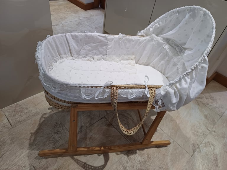 Moses basket, rocking stand, matress, bottom sheet and white bedding.