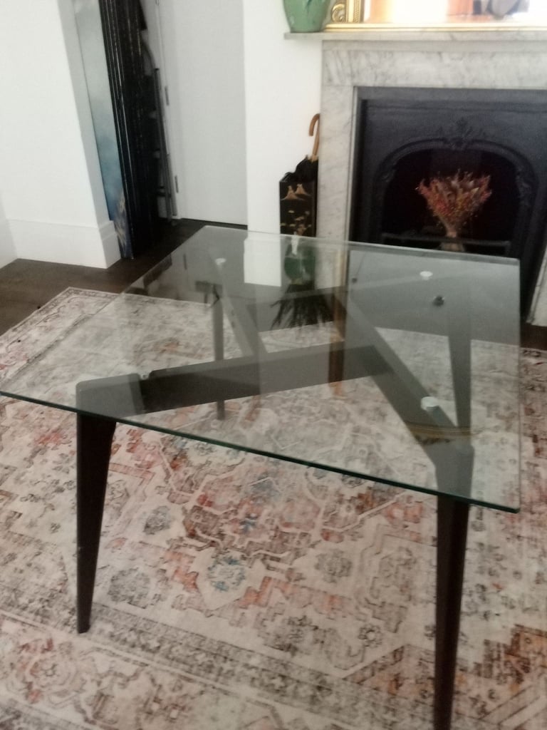 Glass dining table with two black wooden chairs