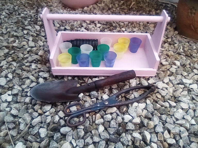 Pink wooden garden trug and gardening accessories.