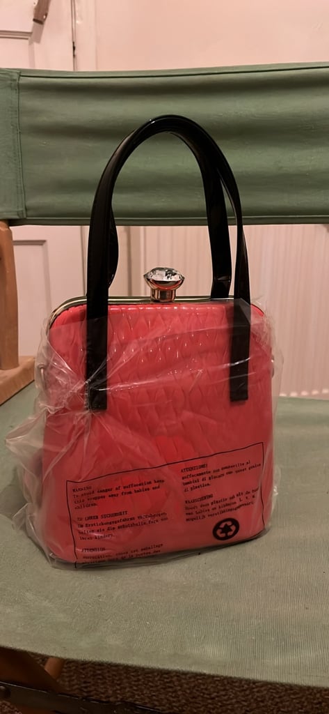 the handbag is a red, box-shaped handbag by the brand Gessy