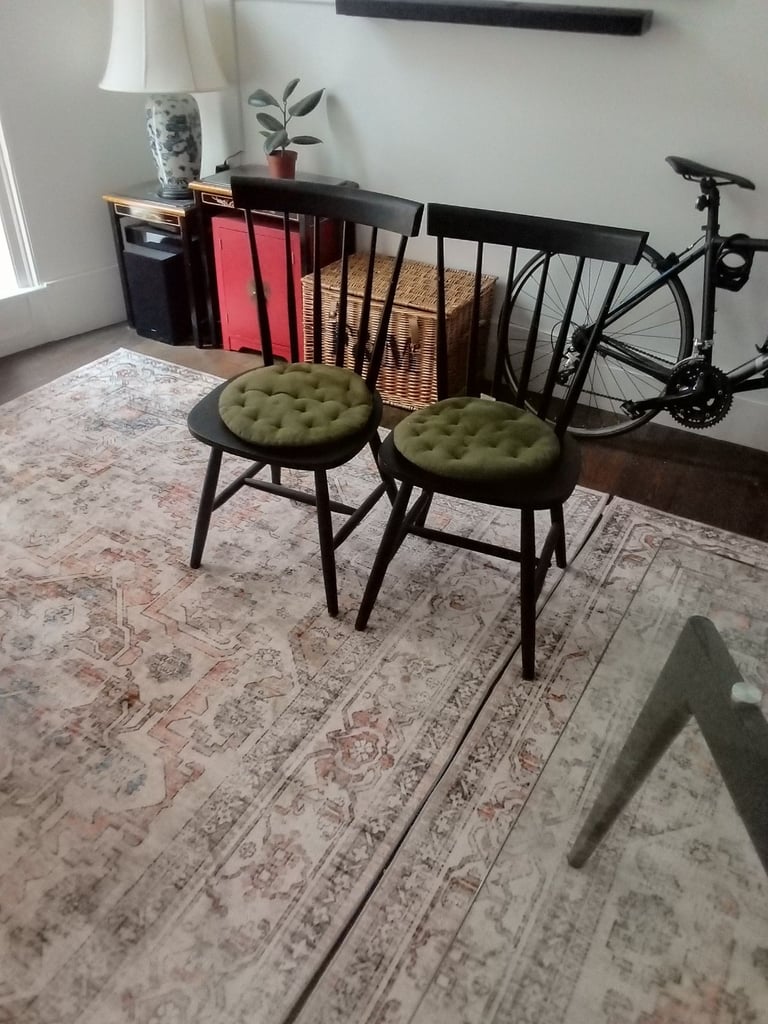 Glass dining table with two black wooden chairs