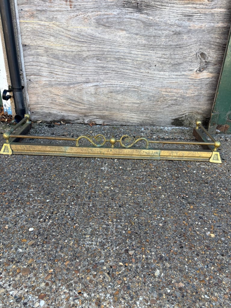 AN ANTIQUE BRASS FIRE PLACE FENDER 