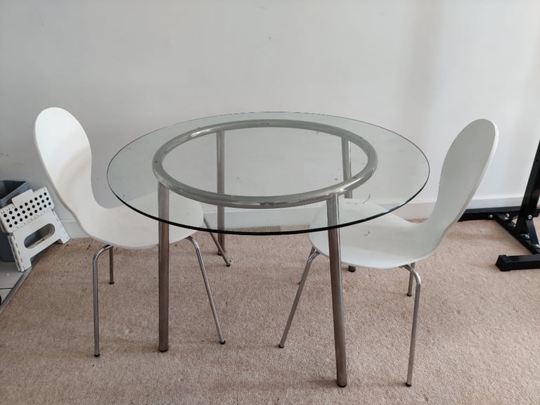 Glass round dining table with white plastic and metal chairs