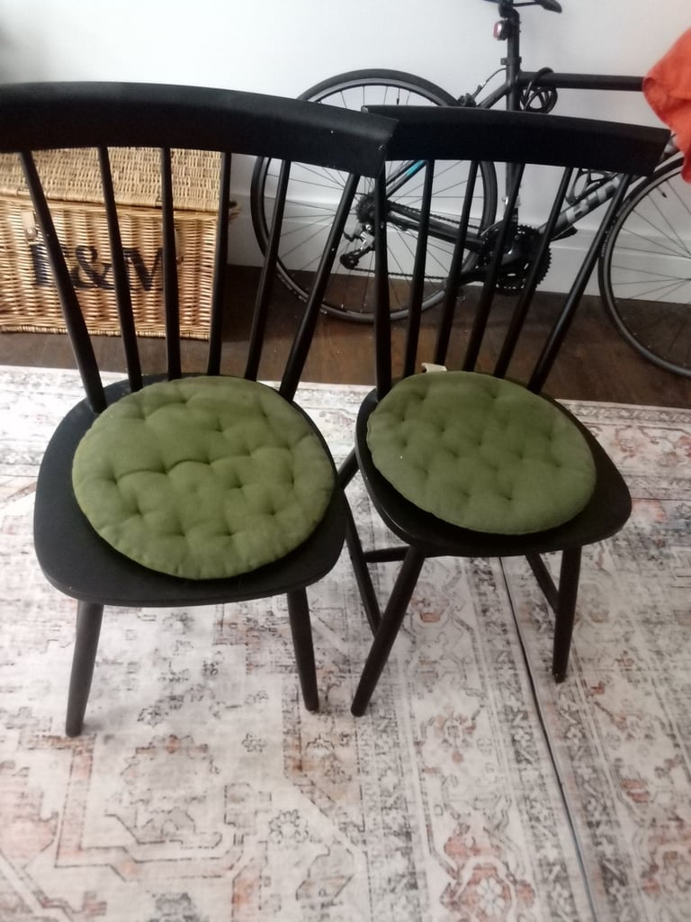 Glass dining table with two black wooden chairs