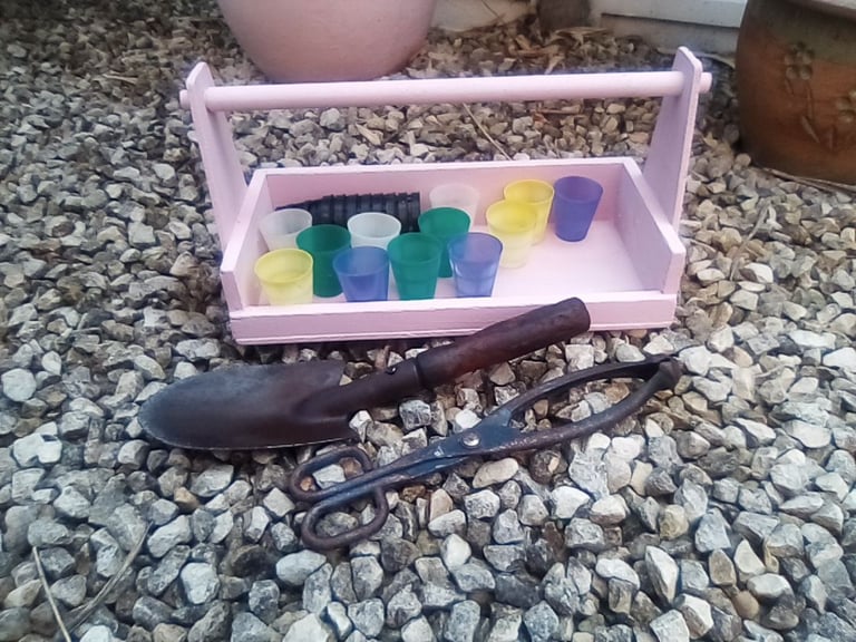 Pink wooden garden trug and gardening accessories.