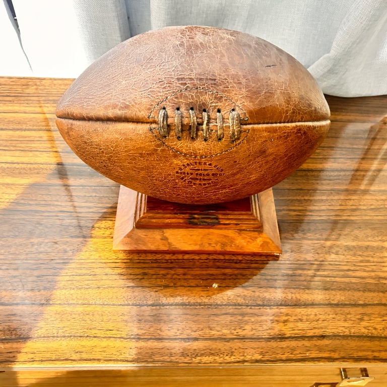 Old leather rugby ball on a wooden plaque vintage