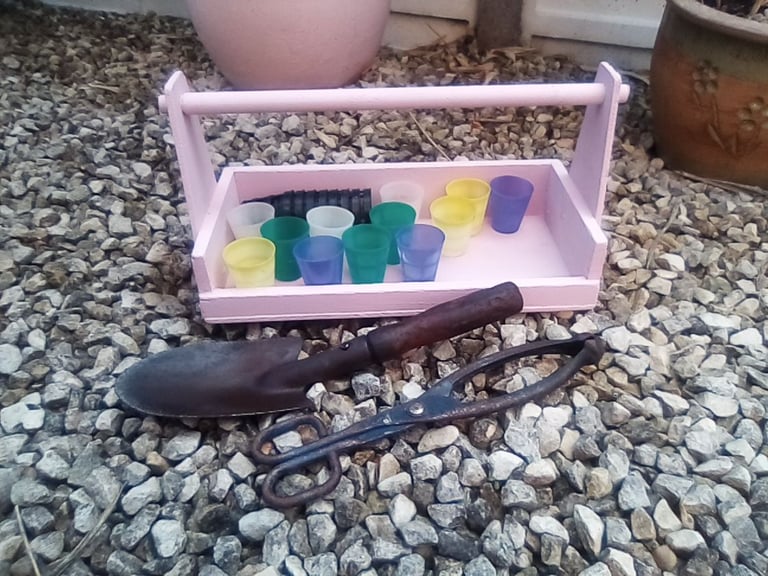 Pink wooden garden trug and gardening accessories.