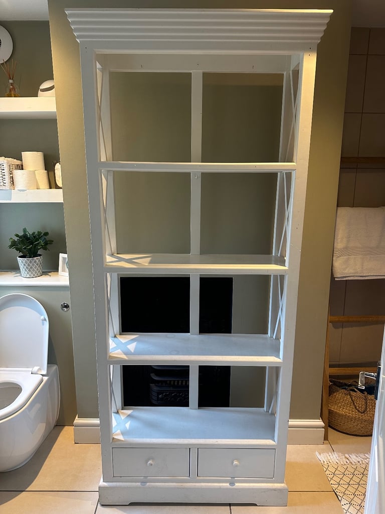 Narrow wooden white shelf unit with drawers.