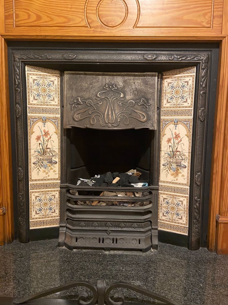 Cast iron fireplace with tiled insert, wooden surround, fireguard and black metal fender 