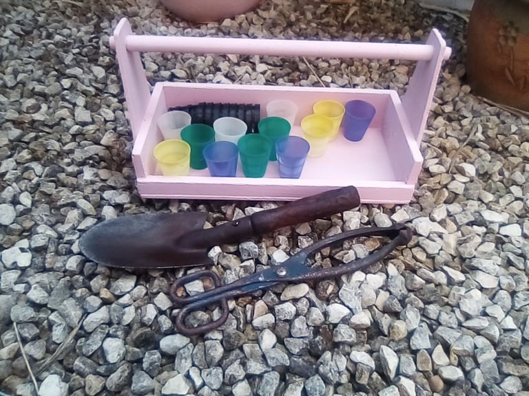 Pink wooden garden trug and gardening accessories.