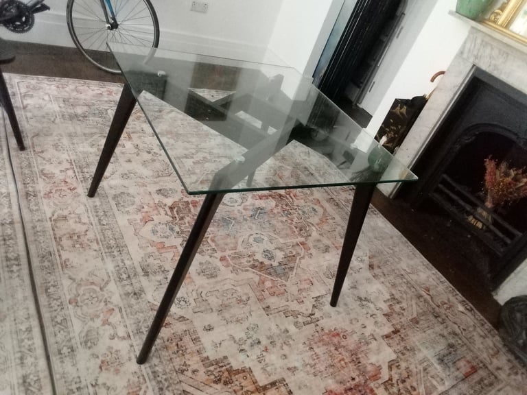 Glass dining table with two black wooden chairs