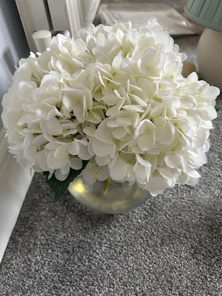 White artificial hydrangeas in a glass vase 