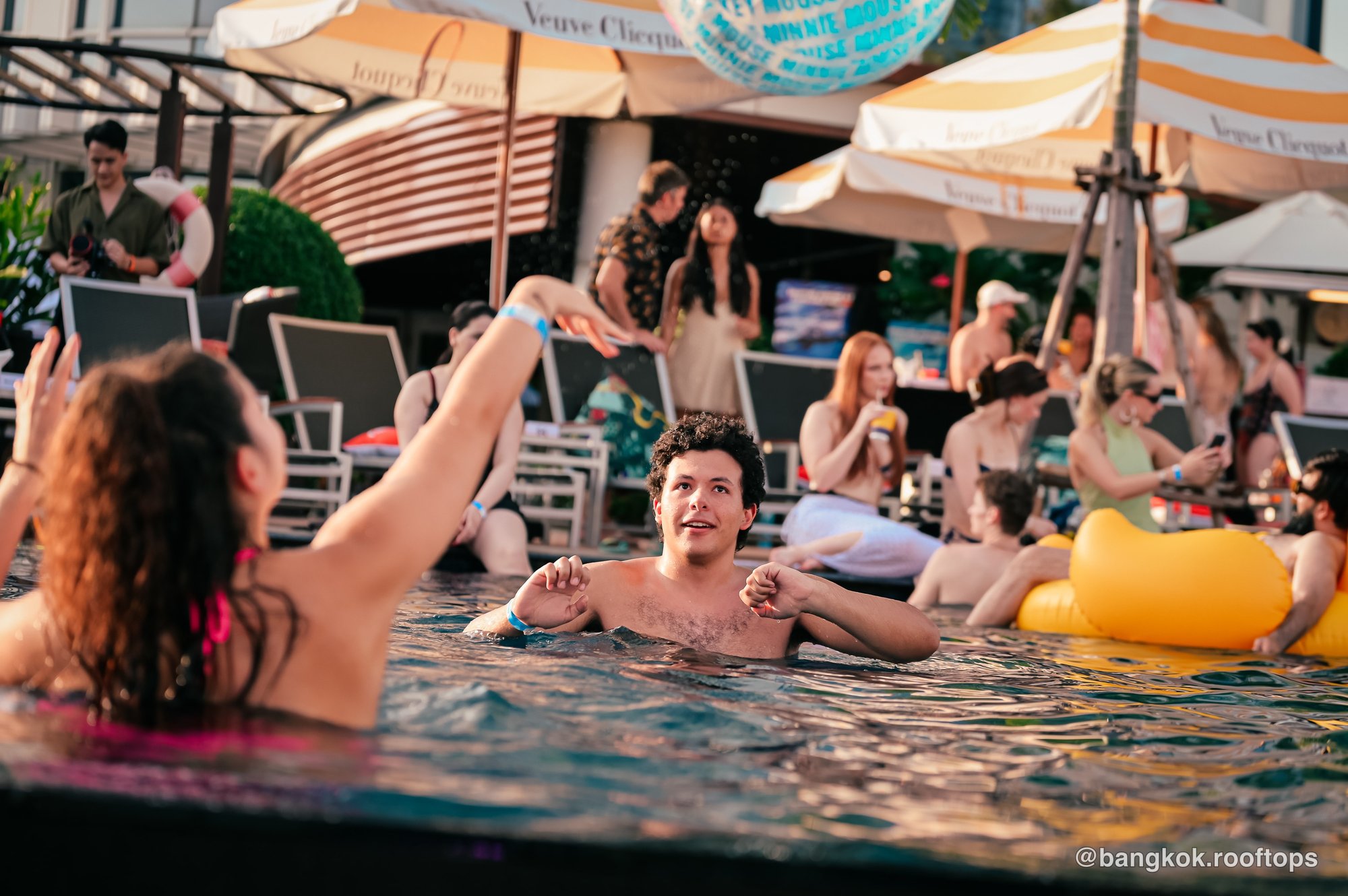 Guests cooling off in the rooftop pool under parasols at a Centara Grand pool party