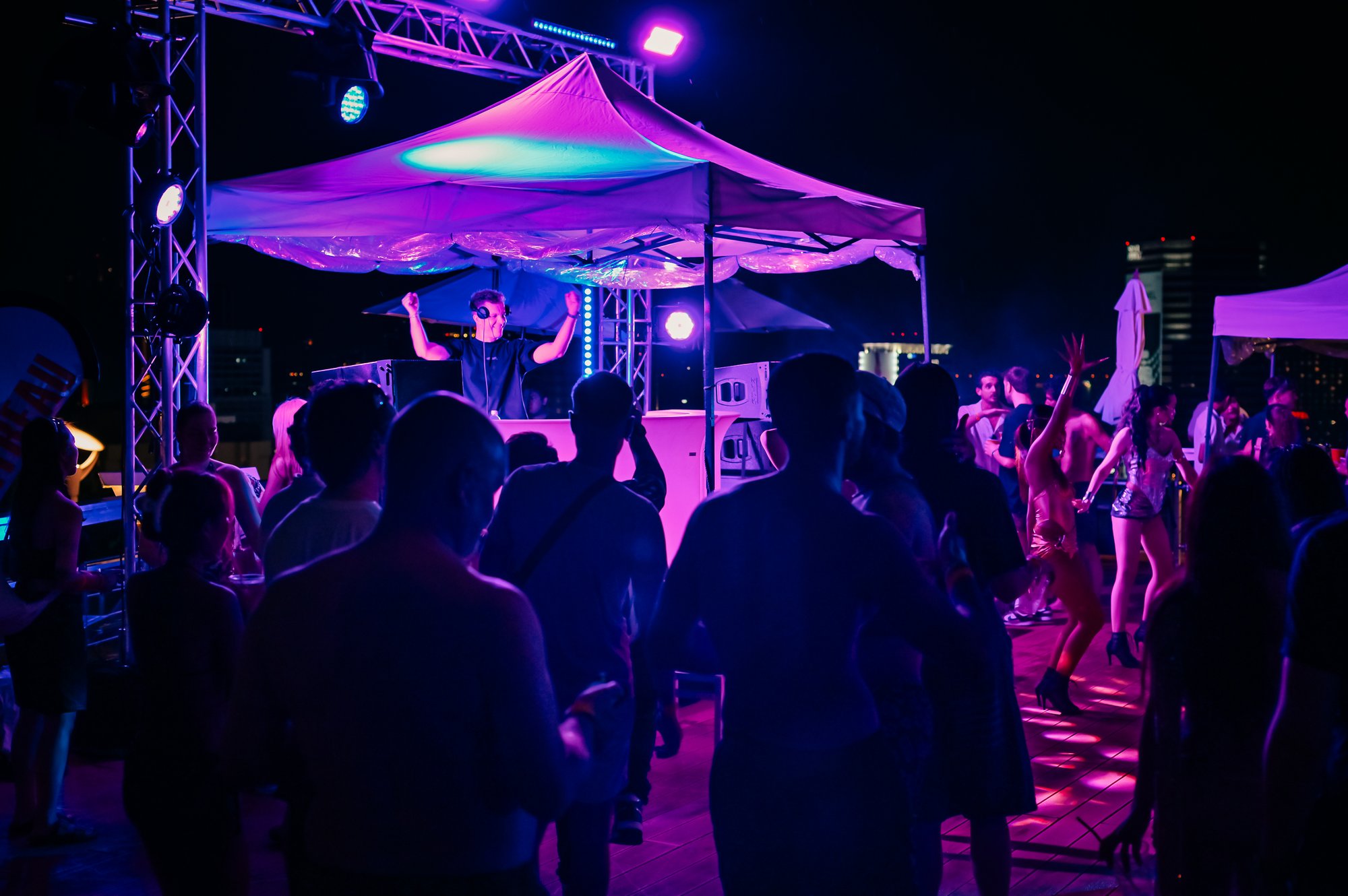 DJ set under neon lights as the dancefloor fills at a Centara Grand rooftop pool party
