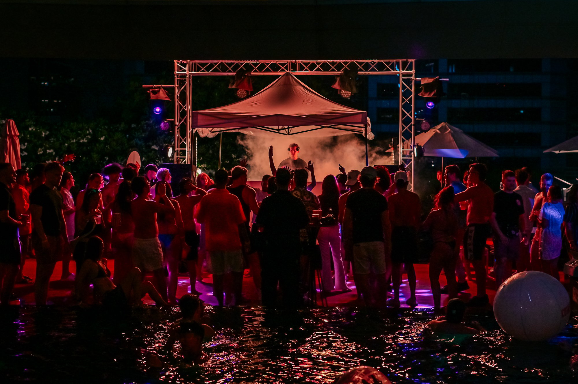 The crowd around the DJ stage at night at a Centara Grand rooftop pool party