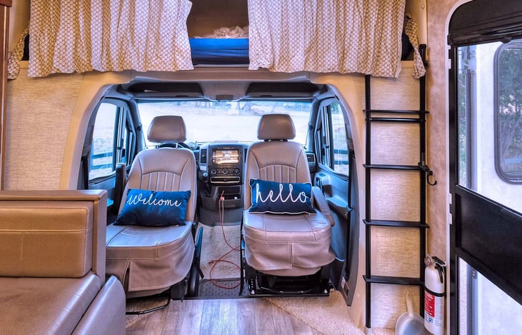 View of the cab with seat swiveled for additional seating. Bed over cab behind curtains.