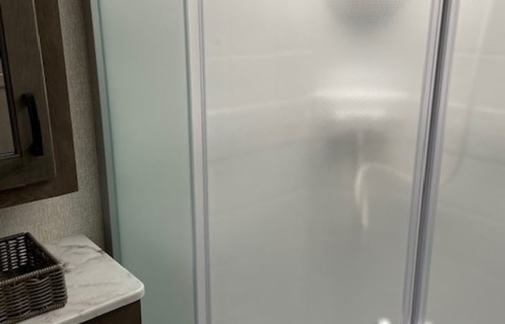 Large shower with tempered glass doors that retract into themselves as a HUGE space saver!