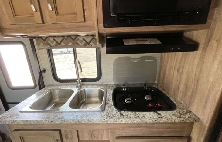 2 burner propane stove, sink and microwave above.