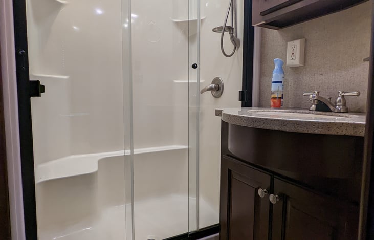 View of full size bathroom with shower skylight and marble top vanity.