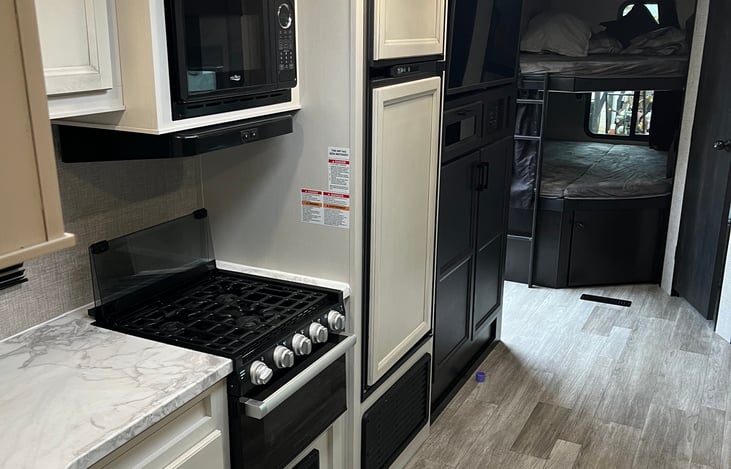 Inside, you'll find a cozy lounge area with a TV equipped with Roku for streaming your favorite shows. Beneath the TV, there's convenient storage space for clothes or gear, helping you stay organized