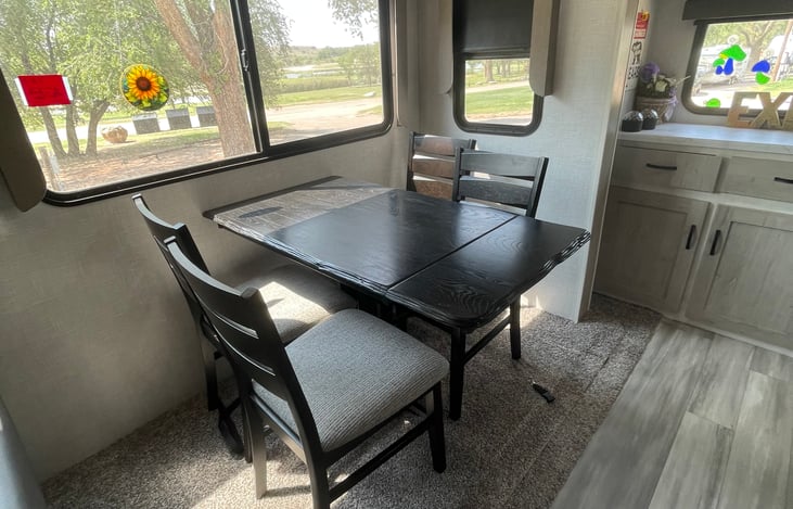 Dining table seats four people and the chairs even have storage! More storage on back wall.