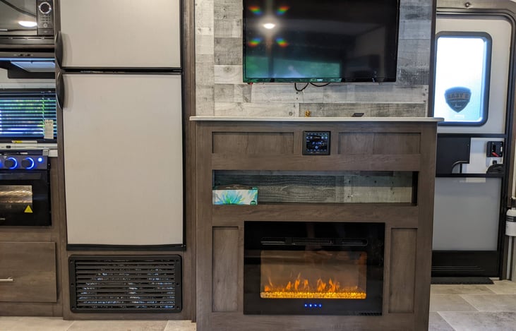 L to R: Oven, microwave, double door refrigerator, tv, entertainment center, fireplace, main entry door.