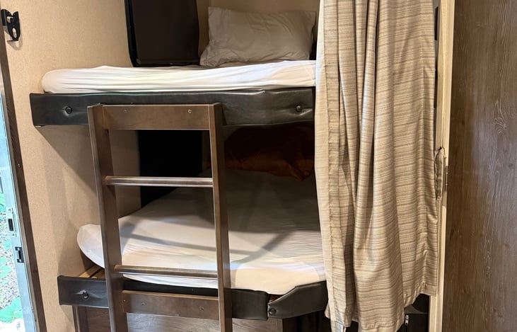 Bunk Beds with sheets, pillows, and blankets.