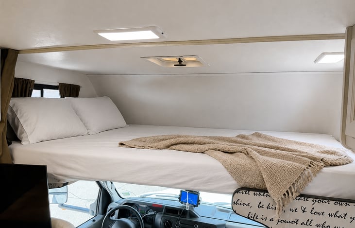 Cozy over-cab RV bed with fresh white linens & pillows – comfortable sleeping for EDC & Burning Man trips