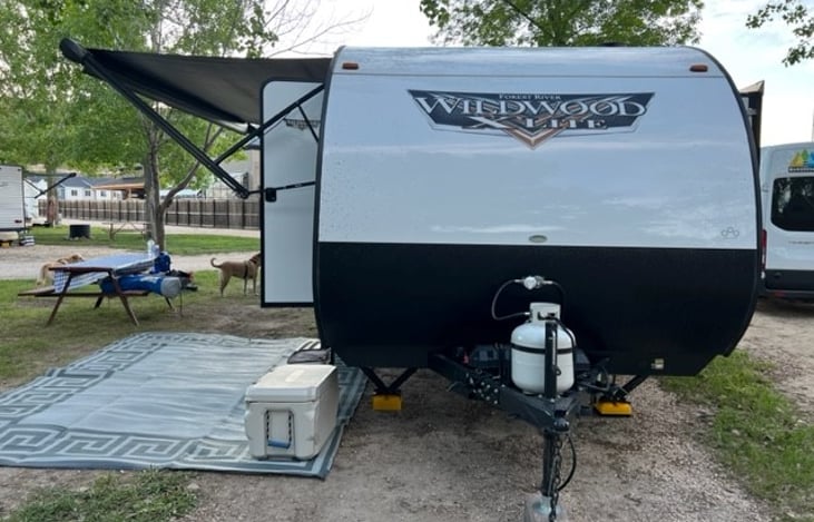 Electric awning with LED lights, large outdoor mat, single propane tank.