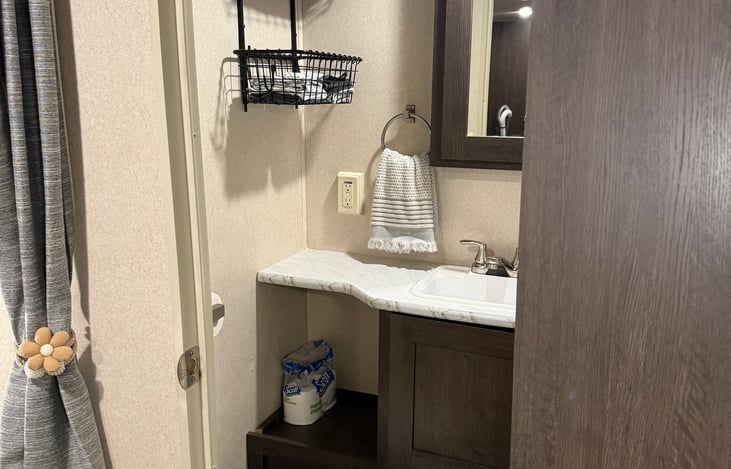 Bathroom includes storage mirror, 5 bath towels, several washcloths, hand towel, toilet brush, toilet paper, and handsoap.