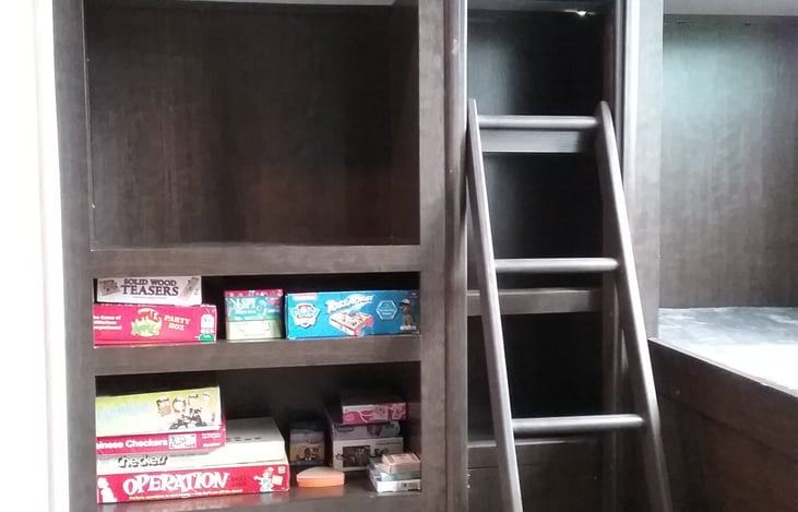 Ladder to top bunk opposite cube couch and games.