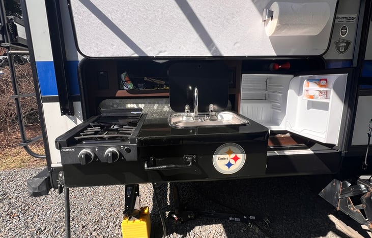 Outdoor kitchen with a hot/cold water sink, 2 gas burners and a minifridge.