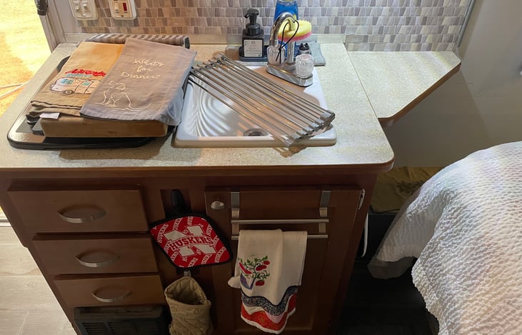 Gas stove, sink, silverware and utensils .