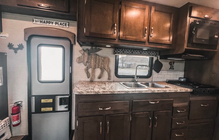 door, kitchen with nice counter space, double sink, convection/microwave oven, spacious cabinets. stocked with single serve coffee pot, toaster, dishes and more.