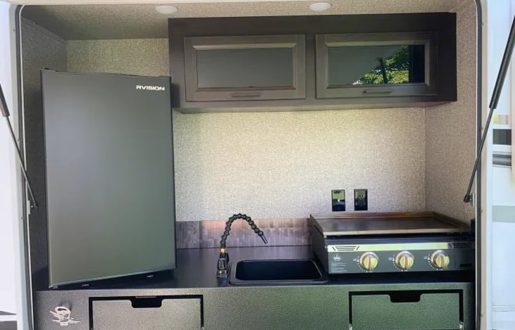 "Blue Grass Beauty" has an outside kitchen equipped with a dual-sided refrigerator, a pull-out sink, specialized condiment storage, and an integrated bottle opener.