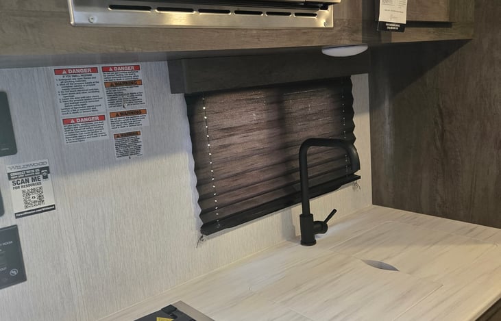Kitchen with sink, microwave, and 2 burner stove.  Sink covers in place for work surface