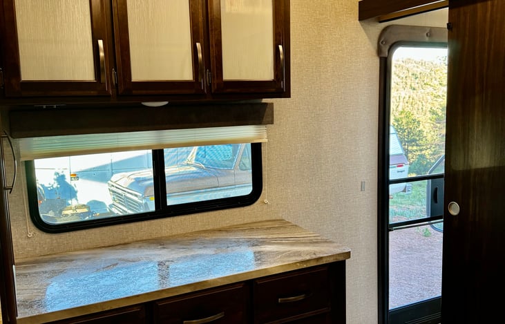 Bedroom  window and storage on the driver side for personal belonging during your stay. The upper cabinets also contain a fan for your comfort and an airbed for additional guests