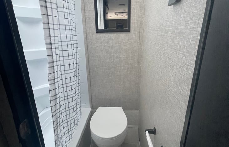 Bathroom toilet, shower curtain, wood frame mirror