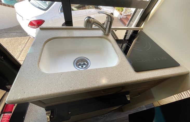 Deep basin sink with house style stainless faucet and induction cooktop.