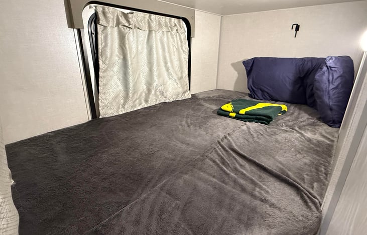 Lower bunk bed with full body pillow and blanket with dedicated LED light truned on.