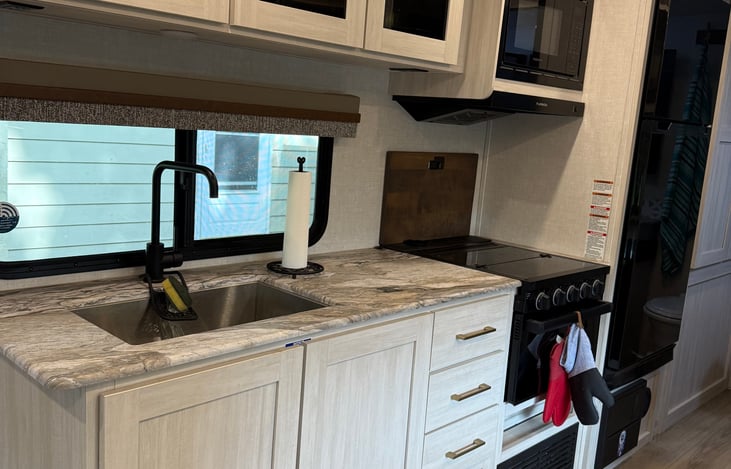 Kitchenette that has a 3 burner stove top, small oven and microwave.