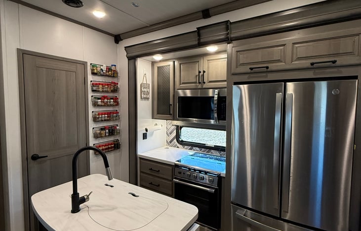 Kitchen with island, 3 burner stove with oven, microwave convection oven, and residential size refrigerator.