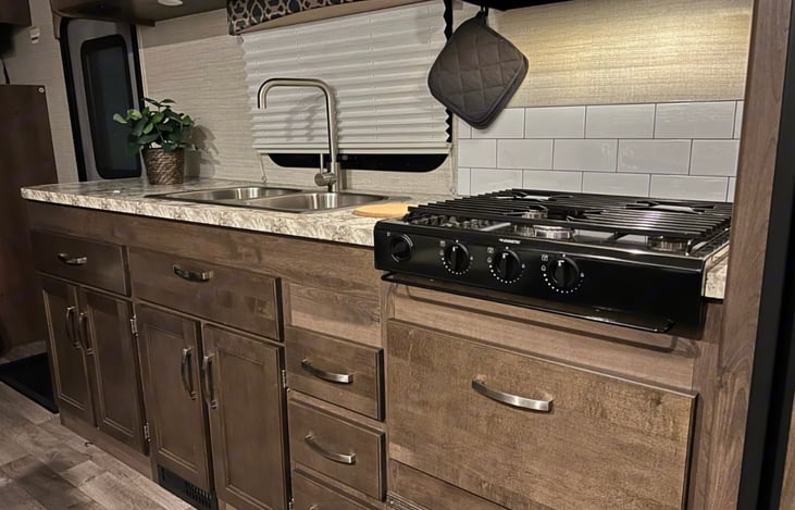 stove top, lower cabinets fully stocked with pots/pans, utensils, cleaning supplies and more.