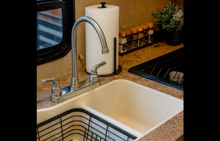 Deep kitchen sink with drying rack and window view.