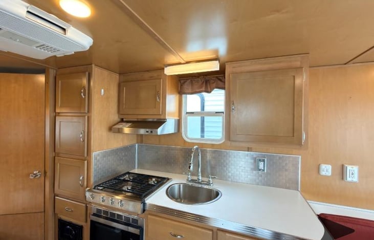 Features include a kitchen sink, gas stove with hood, and microwave.